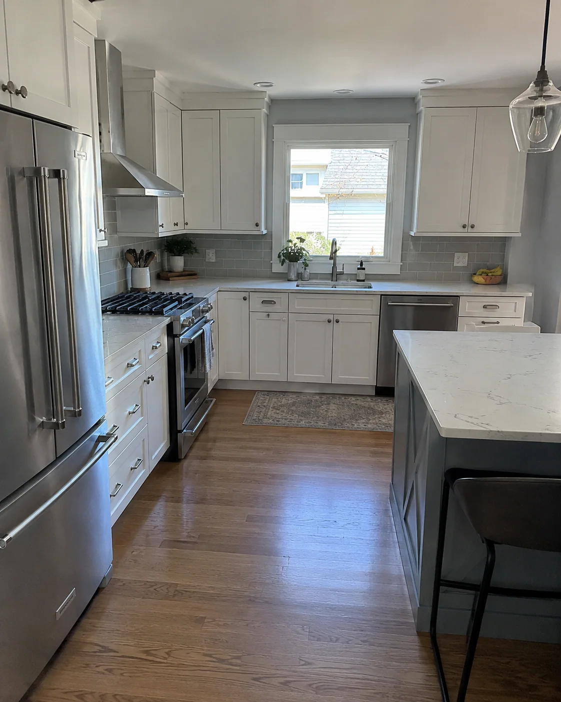 White kitchen cabinets, a light countertop and wood flooring.