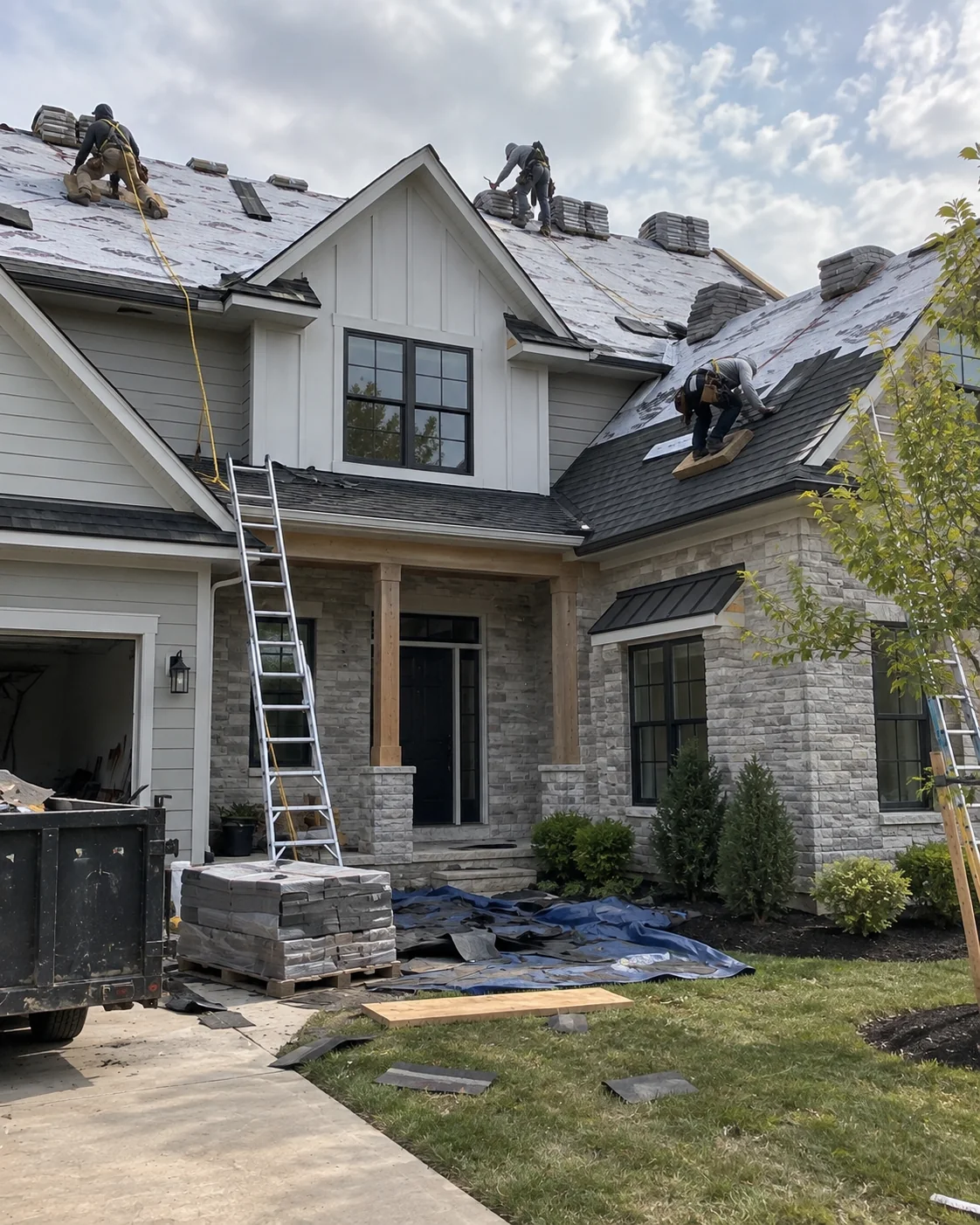 Roofing work in progress on a house with stone and light siding.